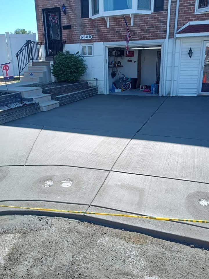 Driveway and garage entrance of a brick house with concrete walkway and curb ramp in the foreground.