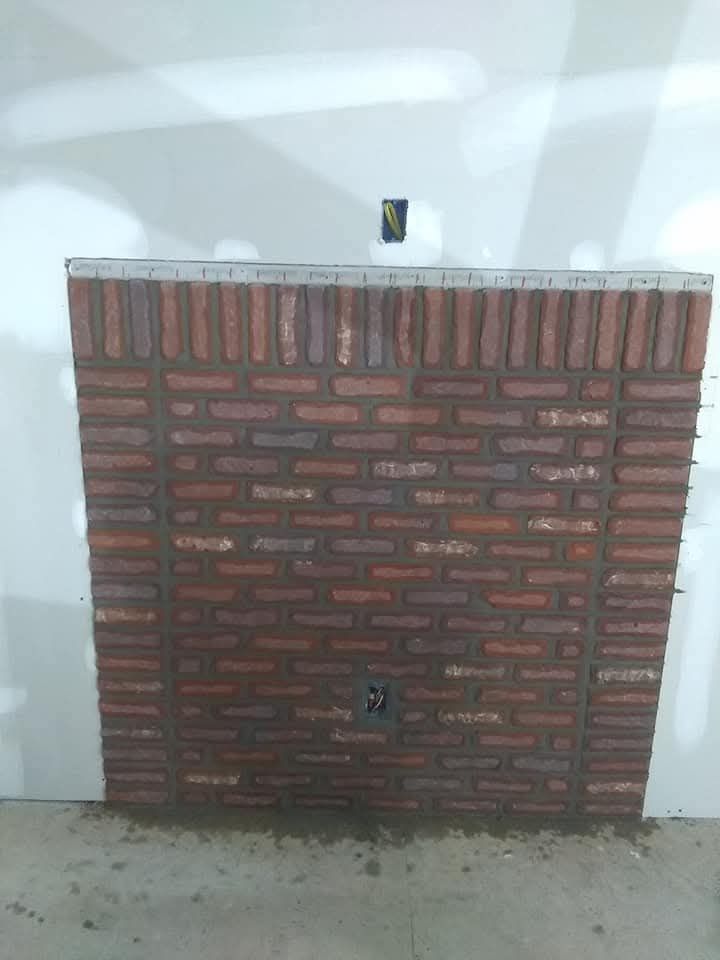 Small brick wall with a white top against a white wall, with a tiny object centered on top.