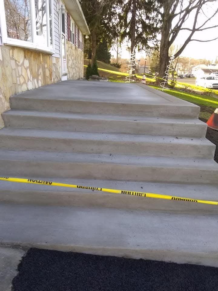 Concrete front steps blocked by yellow caution tape beside a stone building