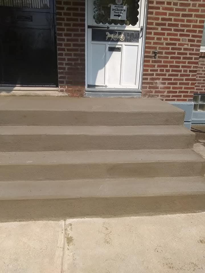 Concrete steps leading to a white front door on a brick house.