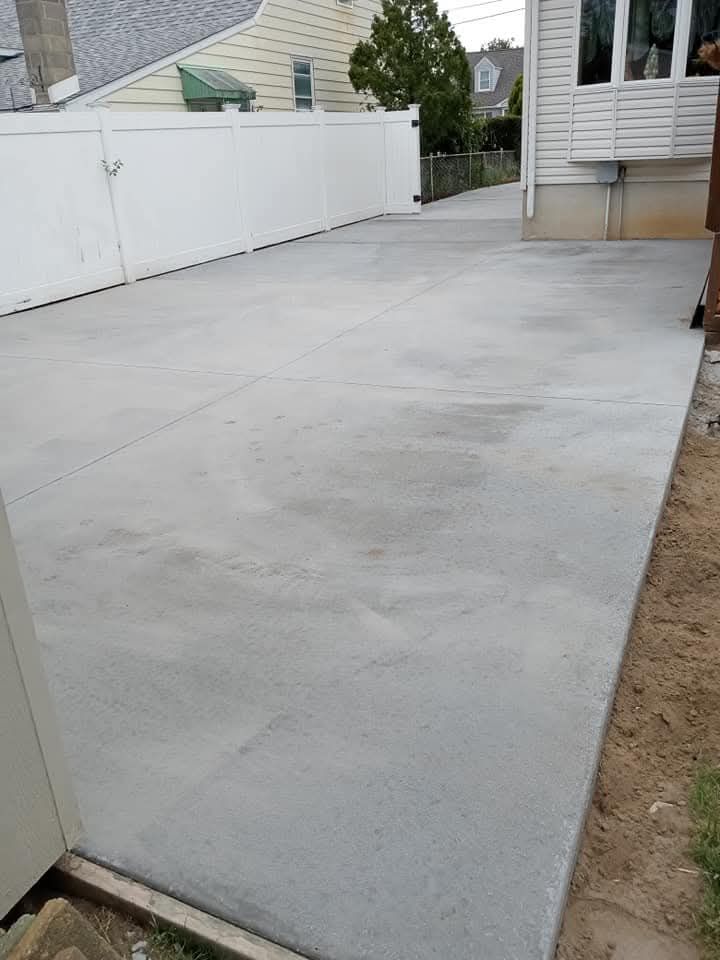 Curved concrete walkway bordered by gravel, leading to a house entrance in a landscaped yard