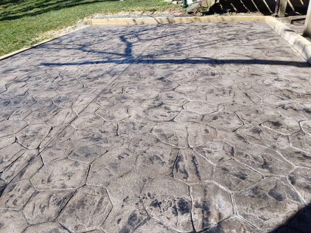 Stamped concrete driveway with cracks and tree shadows in sunlight