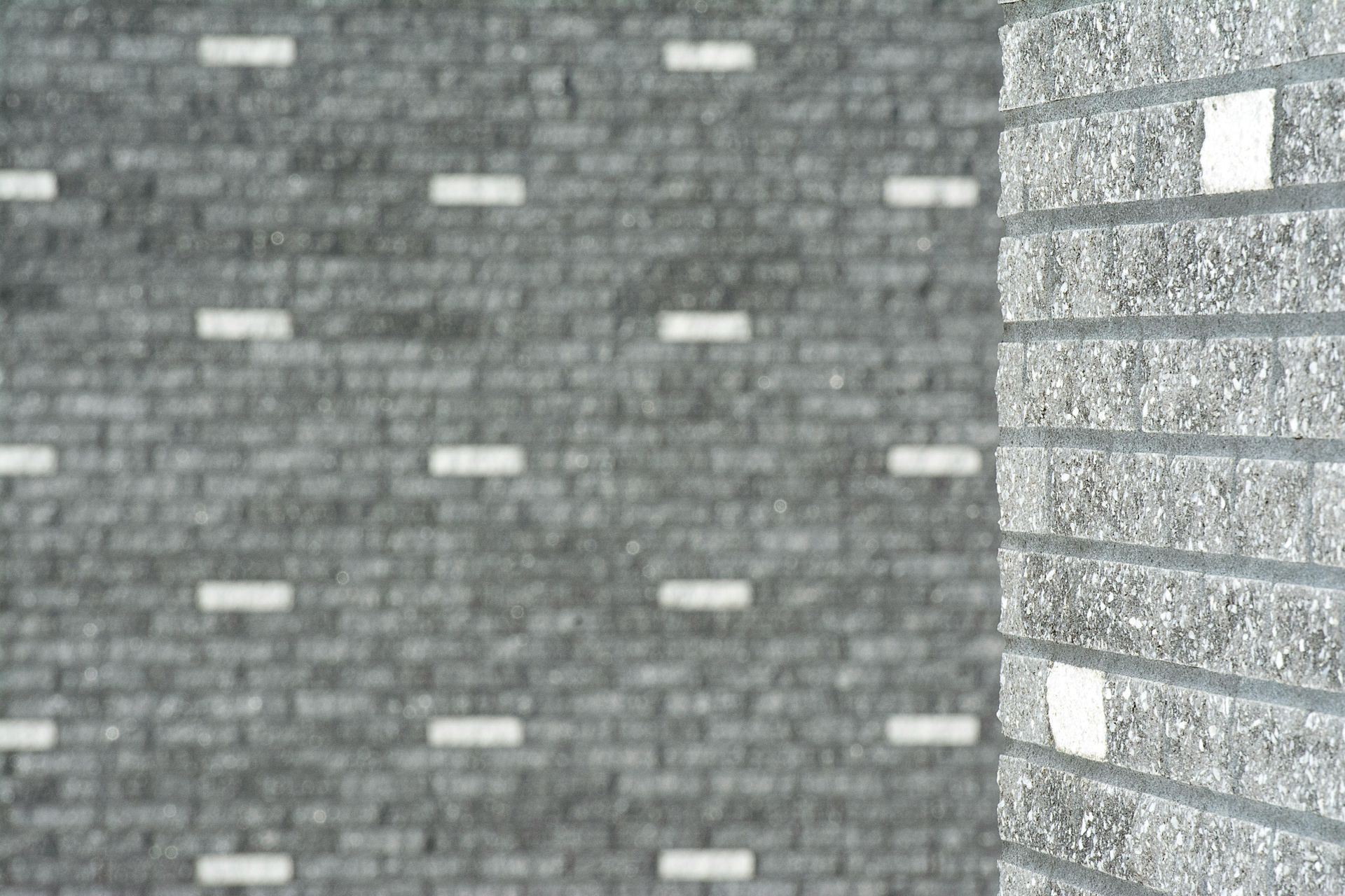 Gray brick wall with small white rectangular accents and a corner view of the building exterior