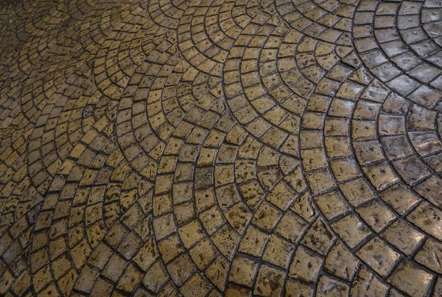 Wet cobblestone pavement with a curved, mosaic-like pattern in brown and gray tones