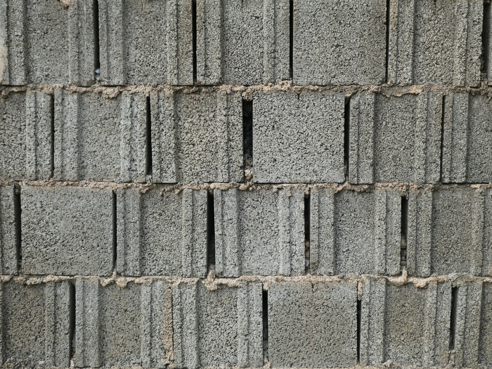 Gray textured brick wall with repeating vertical ridges and staggered blocks