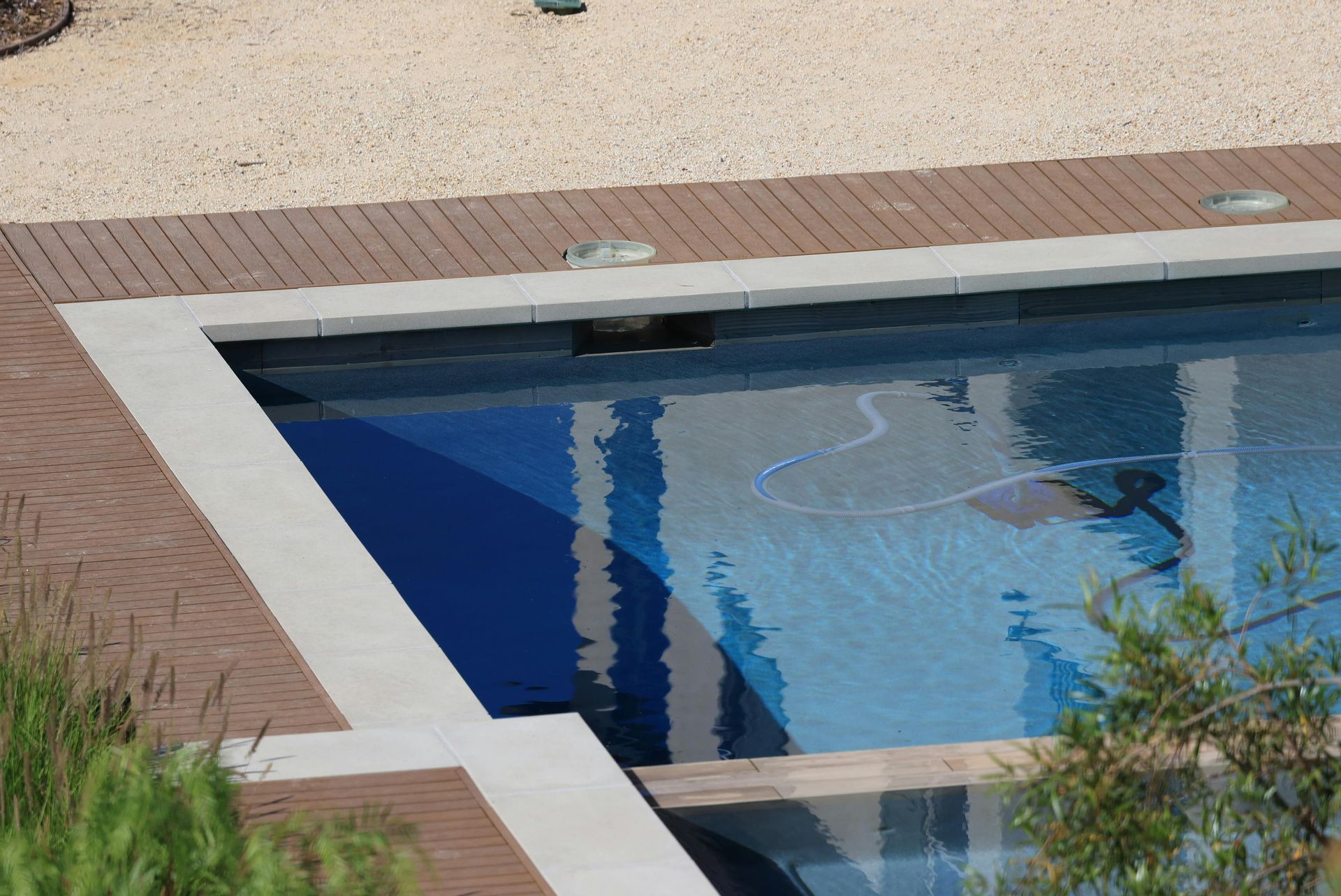 Swimming pool with blue water and a brick-and-concrete deck, viewed from above.