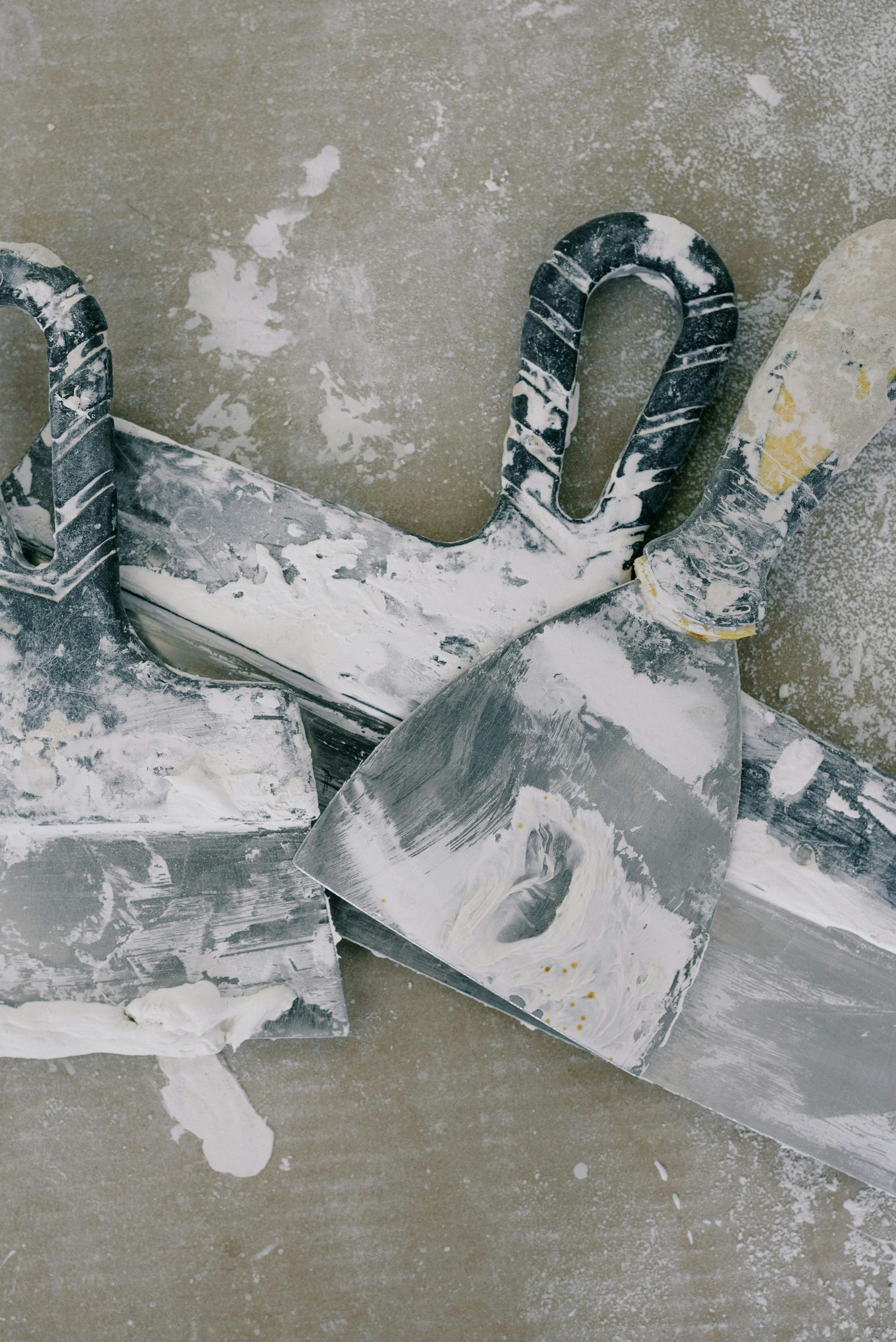Snow-covered metal clamps on a pipe against a concrete wall
