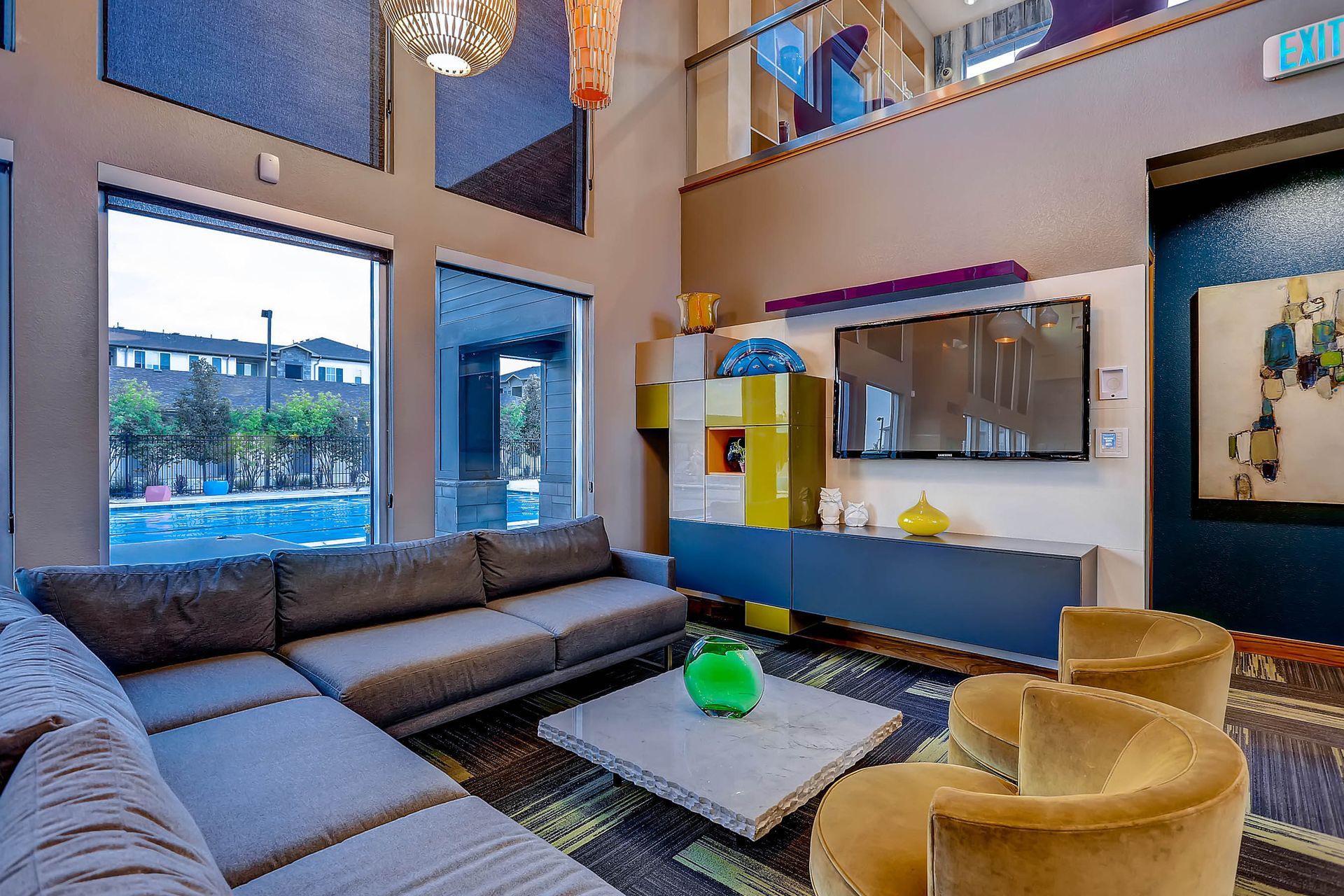 Interior community lounge with a gray sectional sofa, coffee table, and wall-mounted TV.