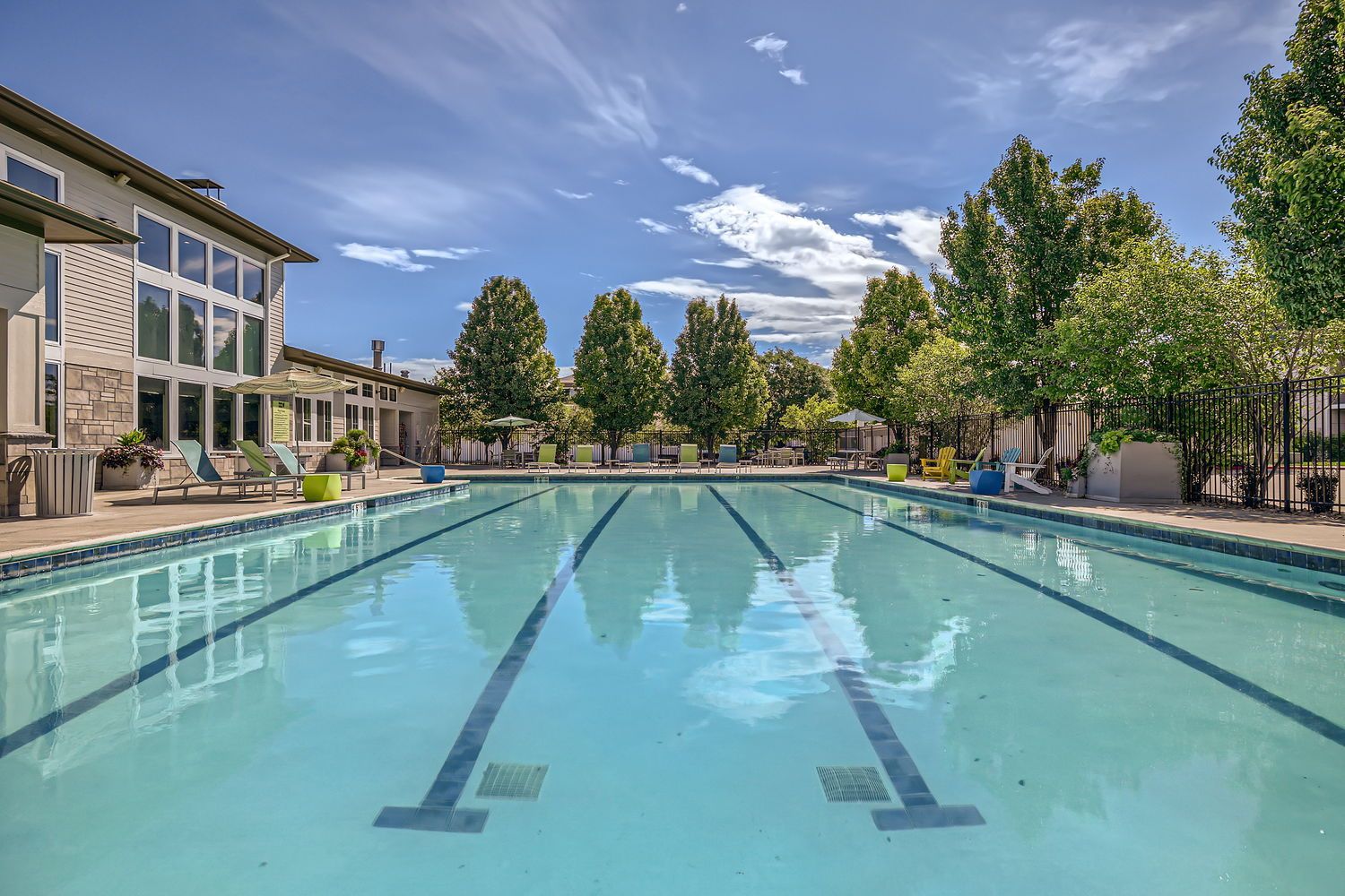 Swimming pool with clear water, blue sky, and trees on a sunny day.