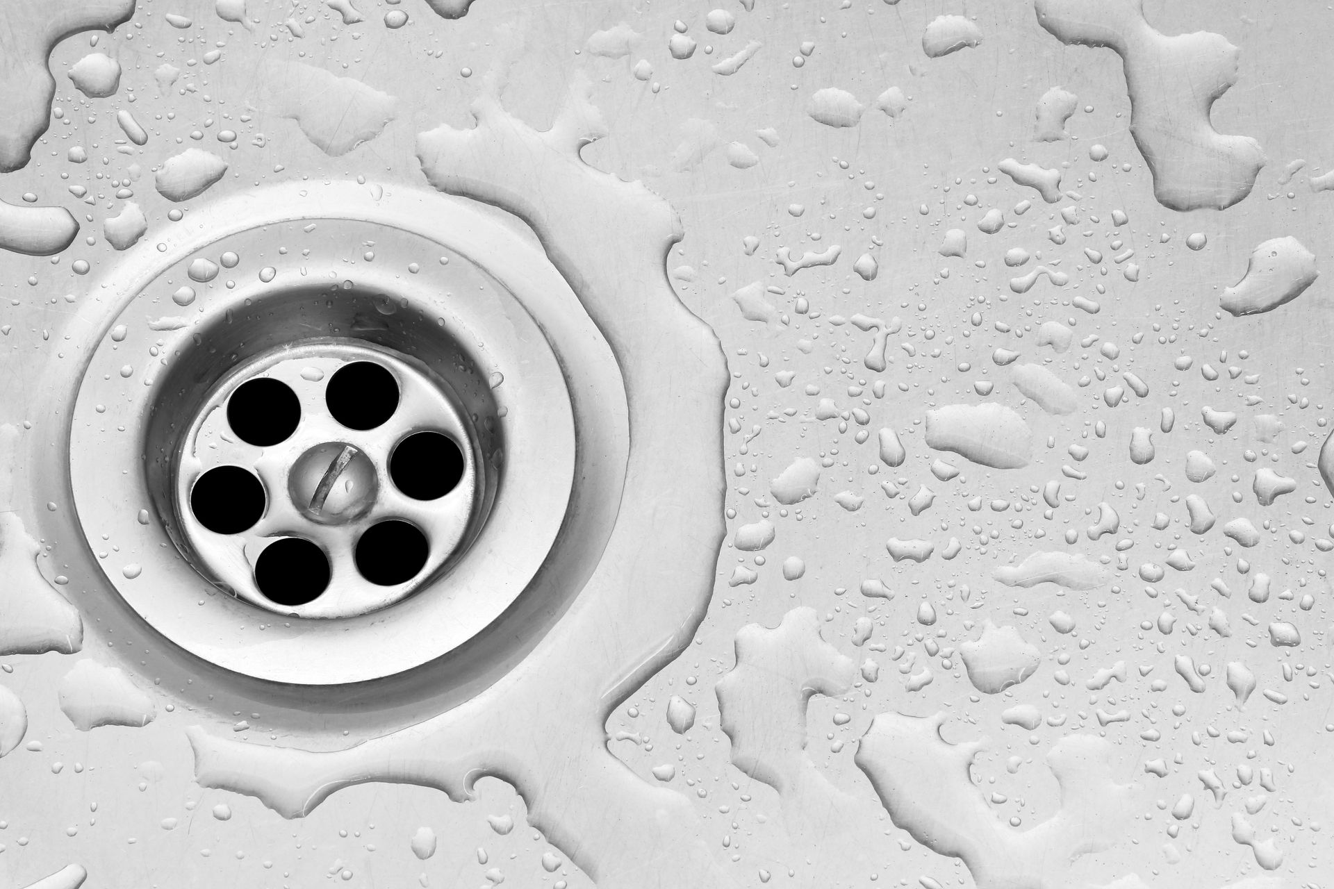 Close-up of a white sink drain with water droplets on the surface Close-up of a white sink drain with water droplets on the surface