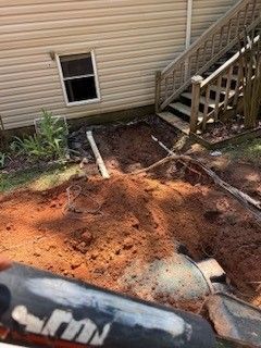 Backyard beside house with exposed dirt patch, pipes, and a wooden stairway