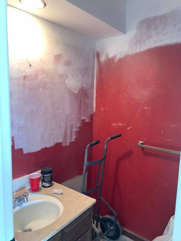 Bathroom being painted red and white, with a sink, walker, and a red cup on the counter.