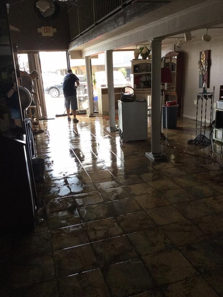 Flooded indoor lobby with a person standing near the bright entrance and reflections on the floor
