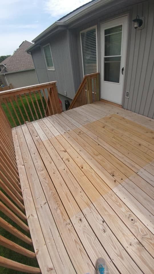New wooden deck beside gray house with railing and white back door