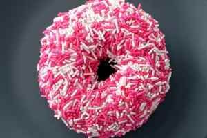 A donut with pink and white sprinkles on it.