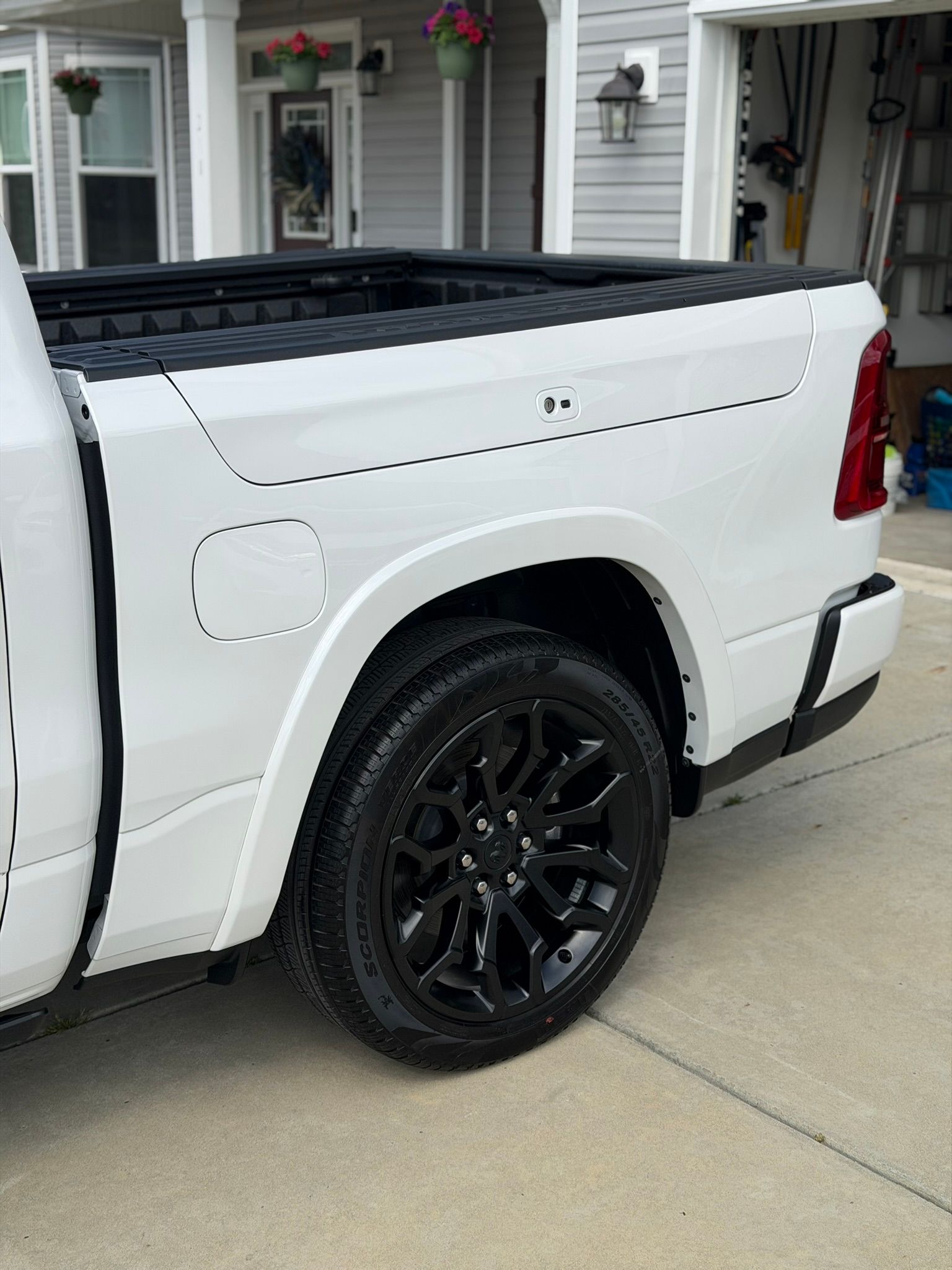 White pickup truck with black wheels parked in a driveway beside a house