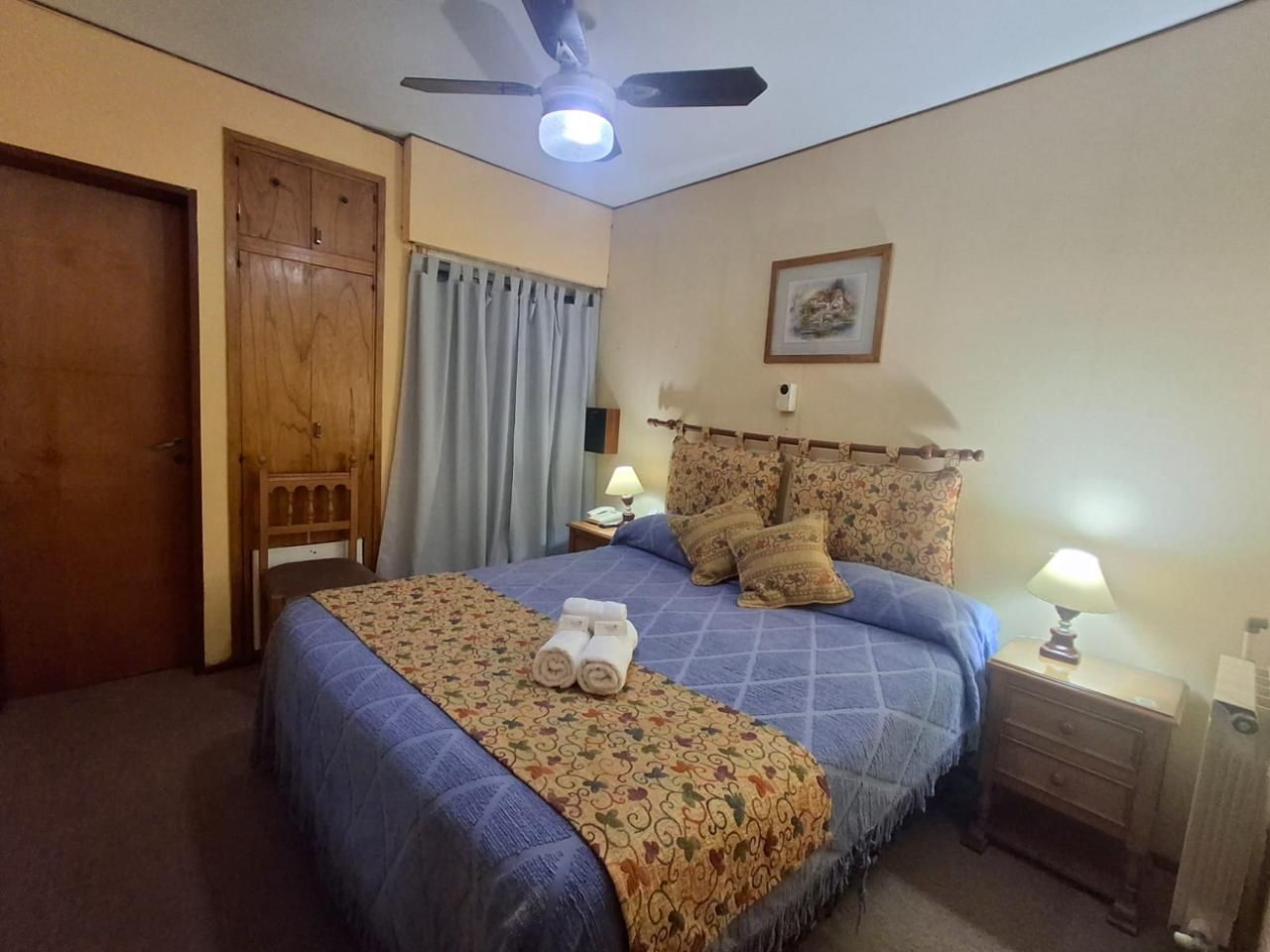 Habitación de hotel moderna con cama king size, escritorio junto a un gran ventanal con vistas a la ciudad y decoración neutra.
