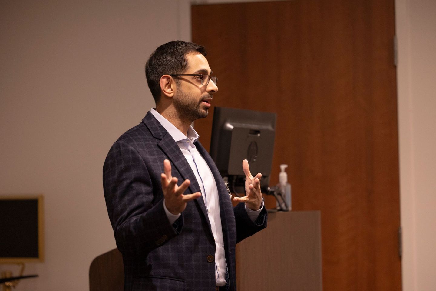 A man in a suit is standing at a podium giving a presentation.