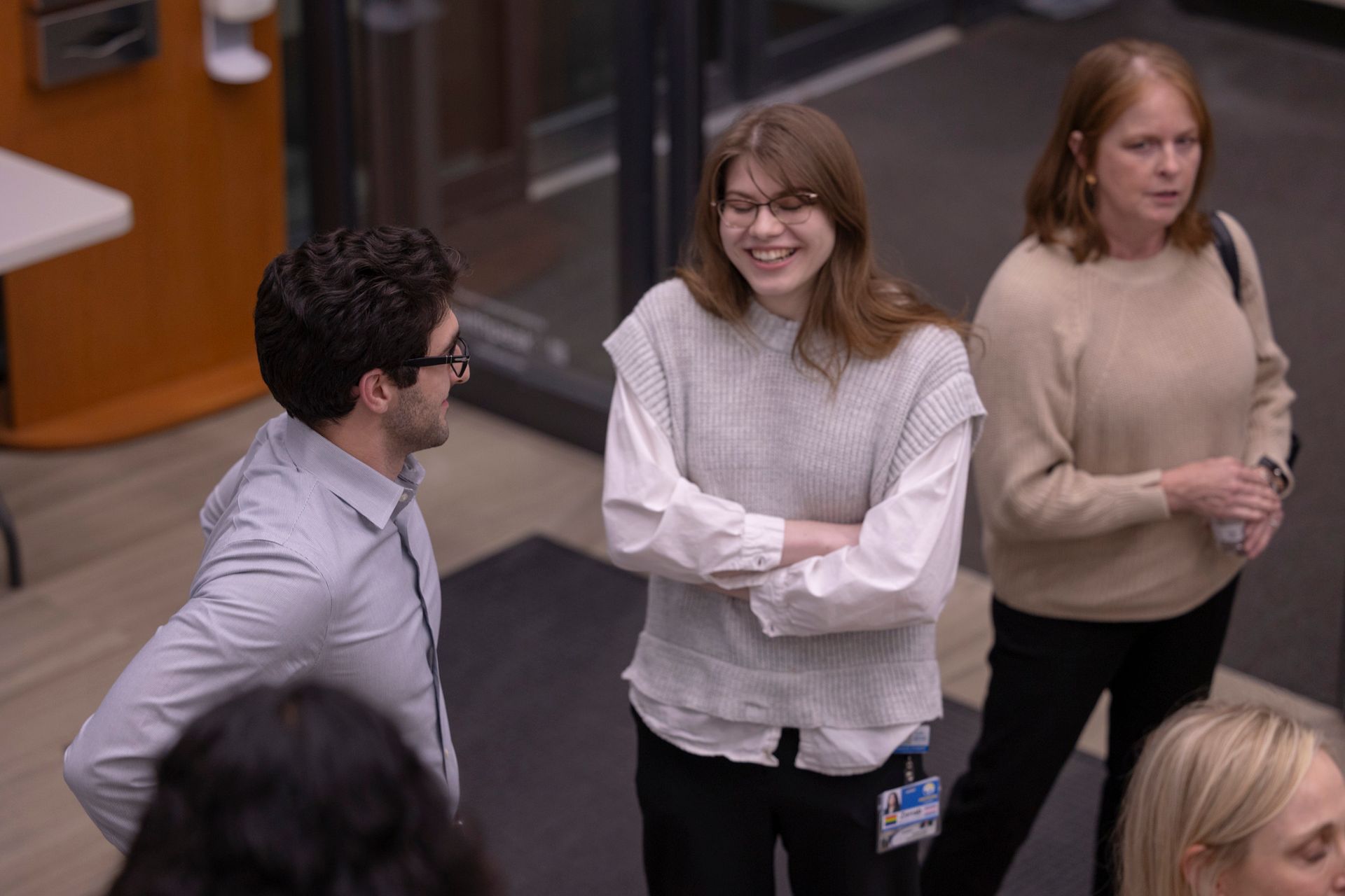 A group of people are standing in a hallway talking to each other.