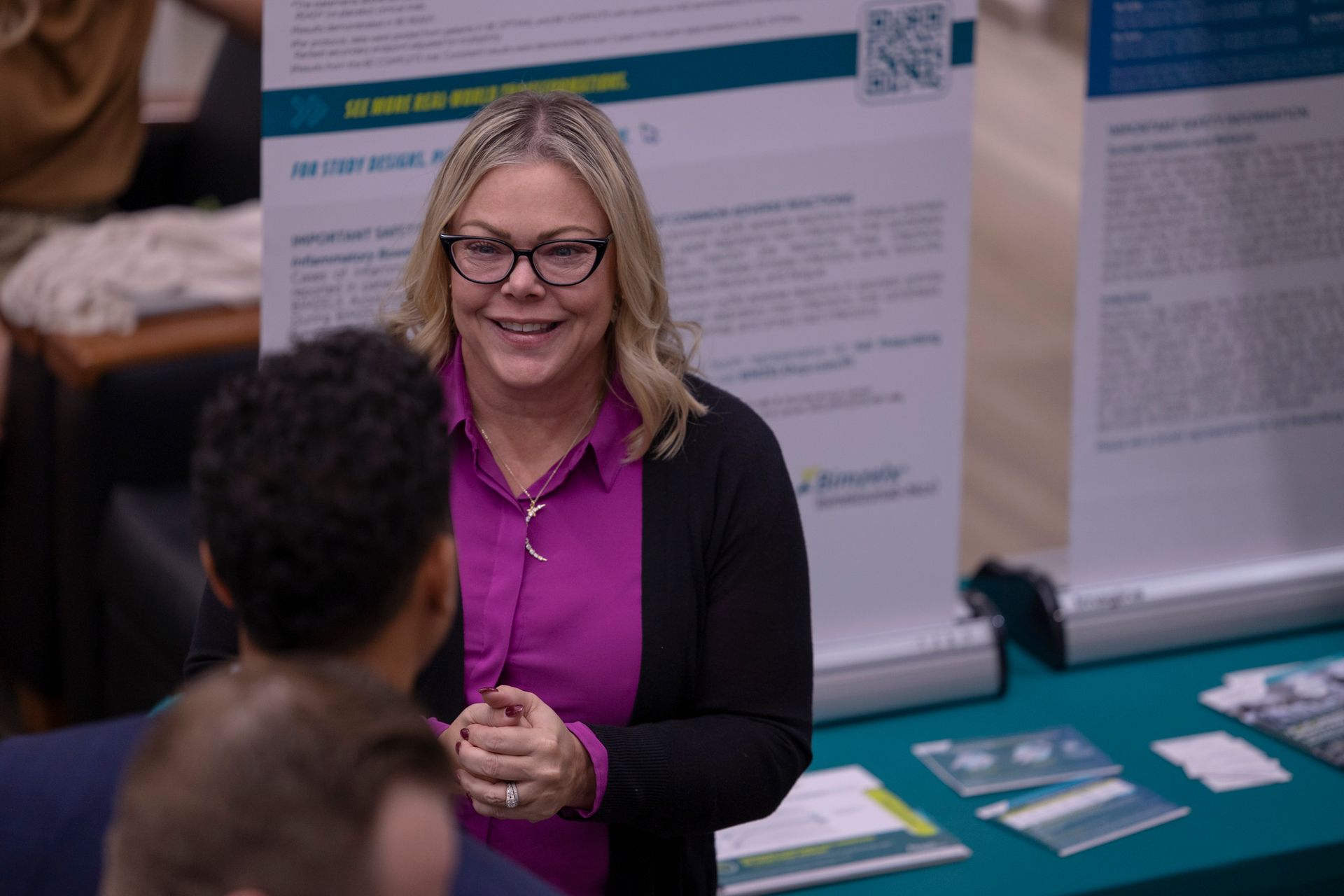A woman is standing in front of a table talking to a man.