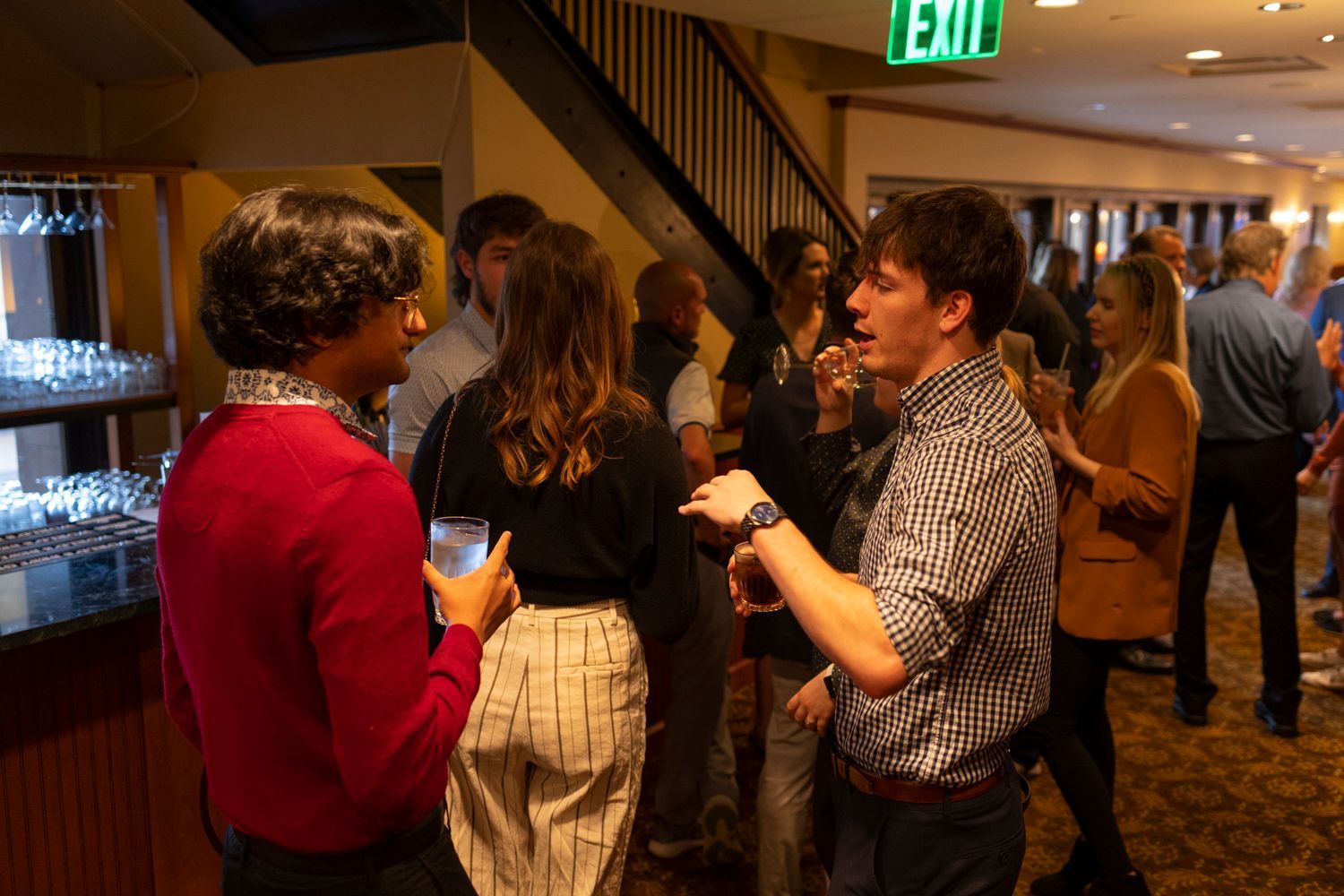 A group of people are standing in a room talking to each other.