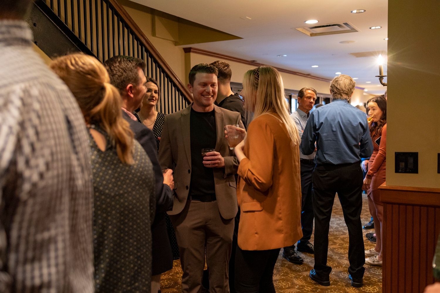 A group of people are standing in a room talking to each other.