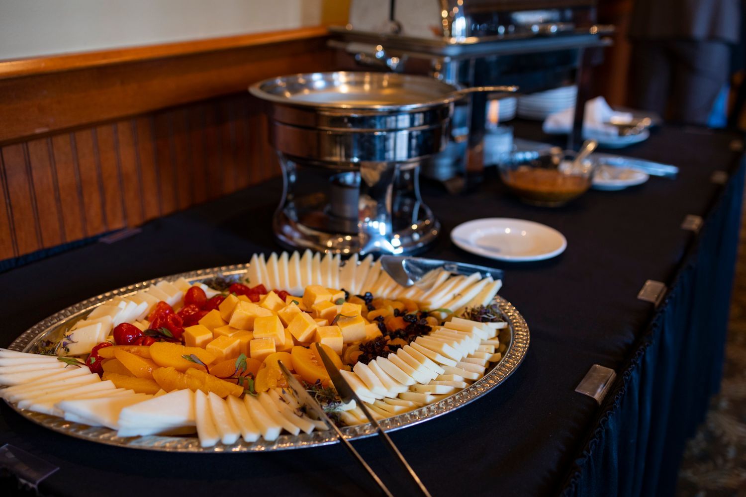 A buffet table with a tray of cheese and fruit on it.