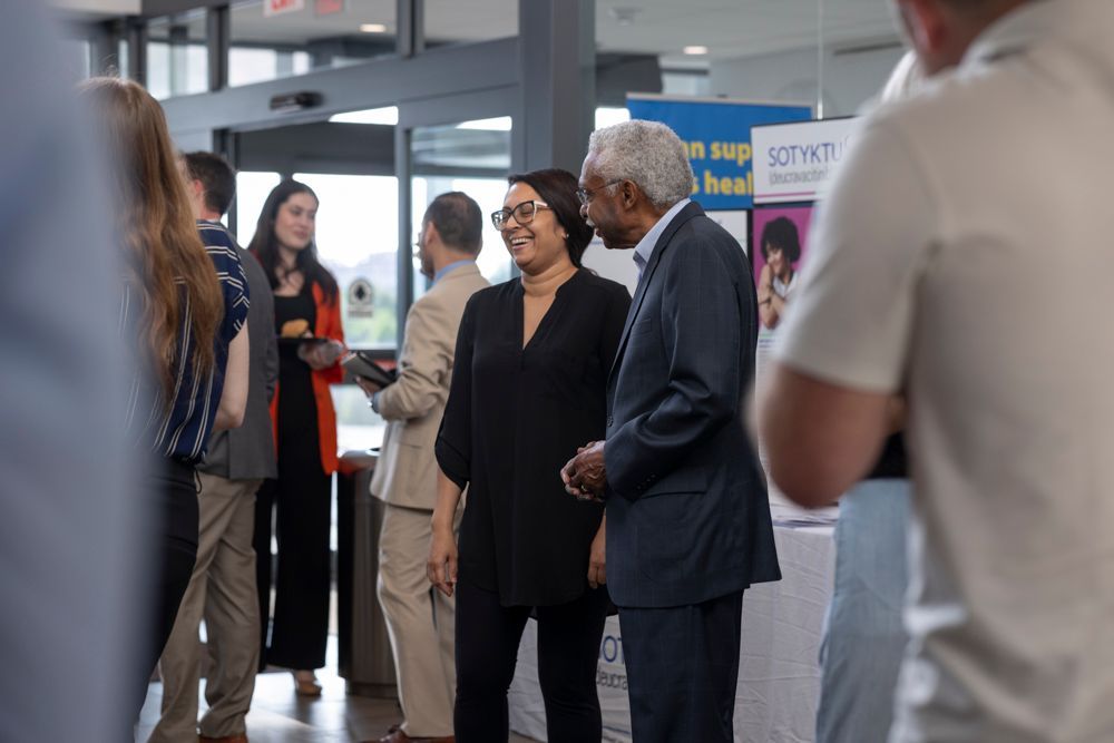 A group of people are standing in a room talking to each other.