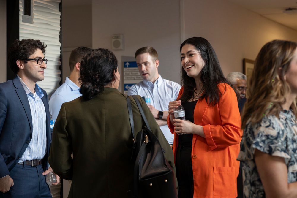 A group of people are standing in a room talking to each other.