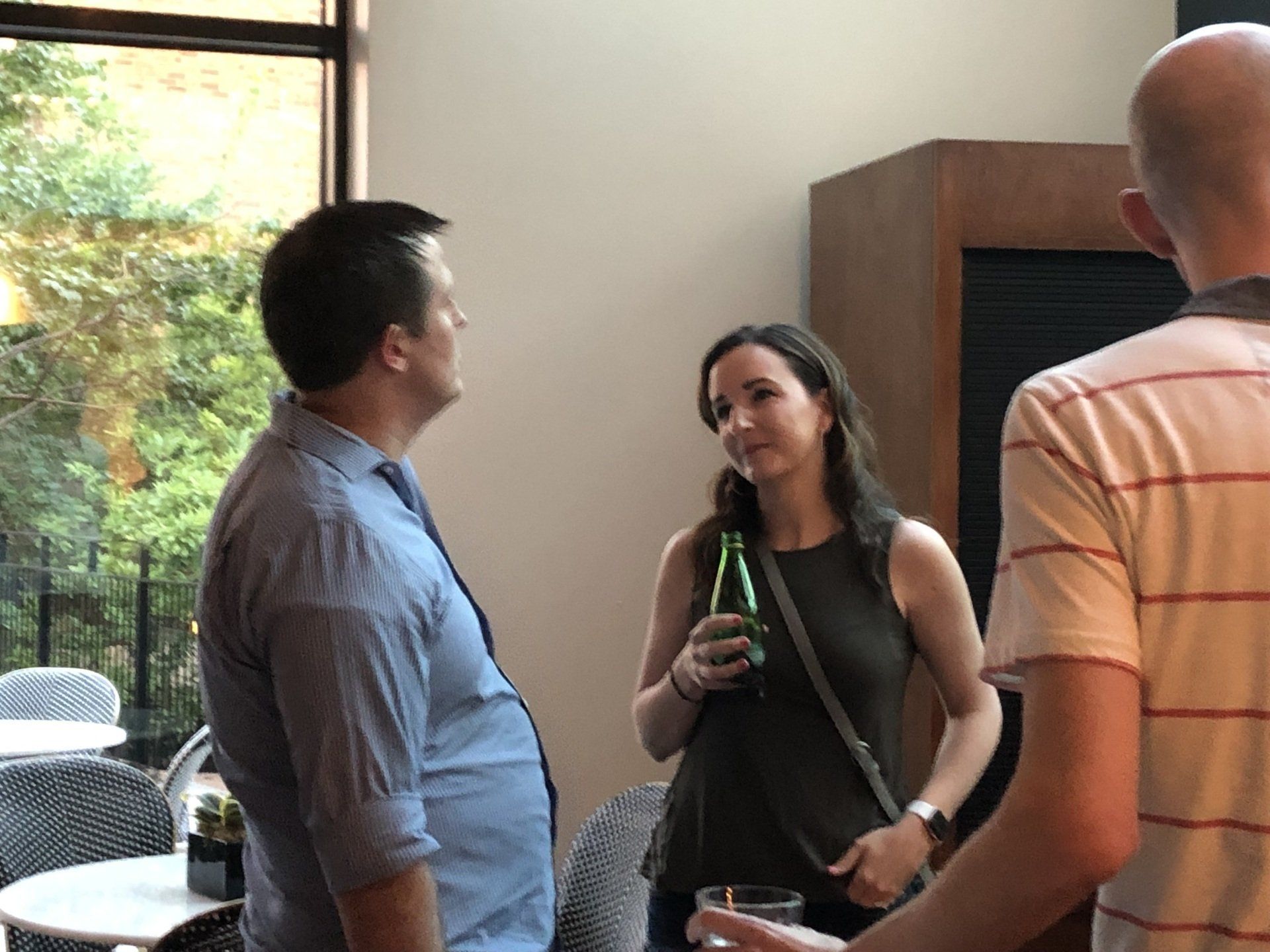 A group of people are standing in a room talking to each other.