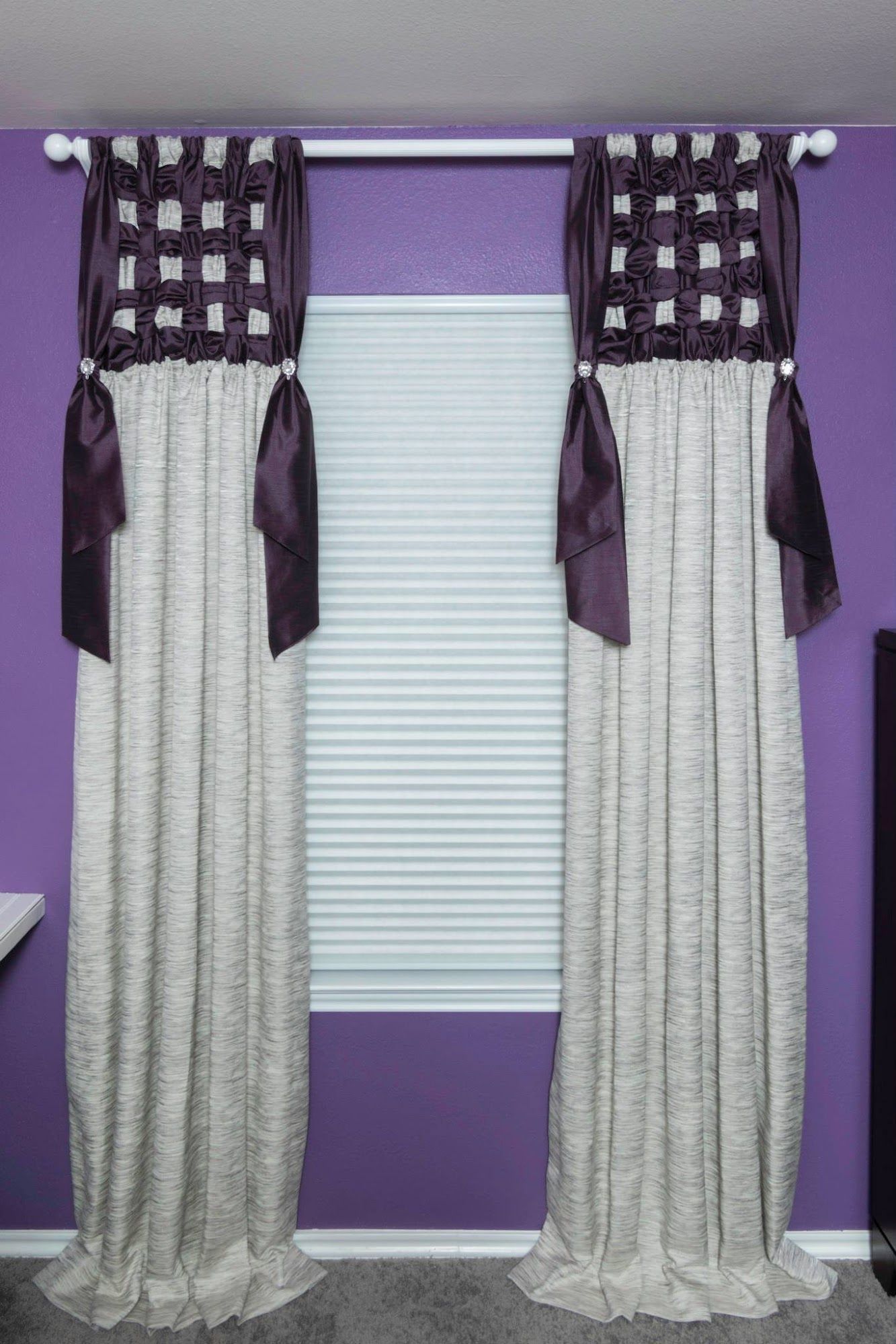 A pair of curtains are hanging on a window in a room with purple walls.