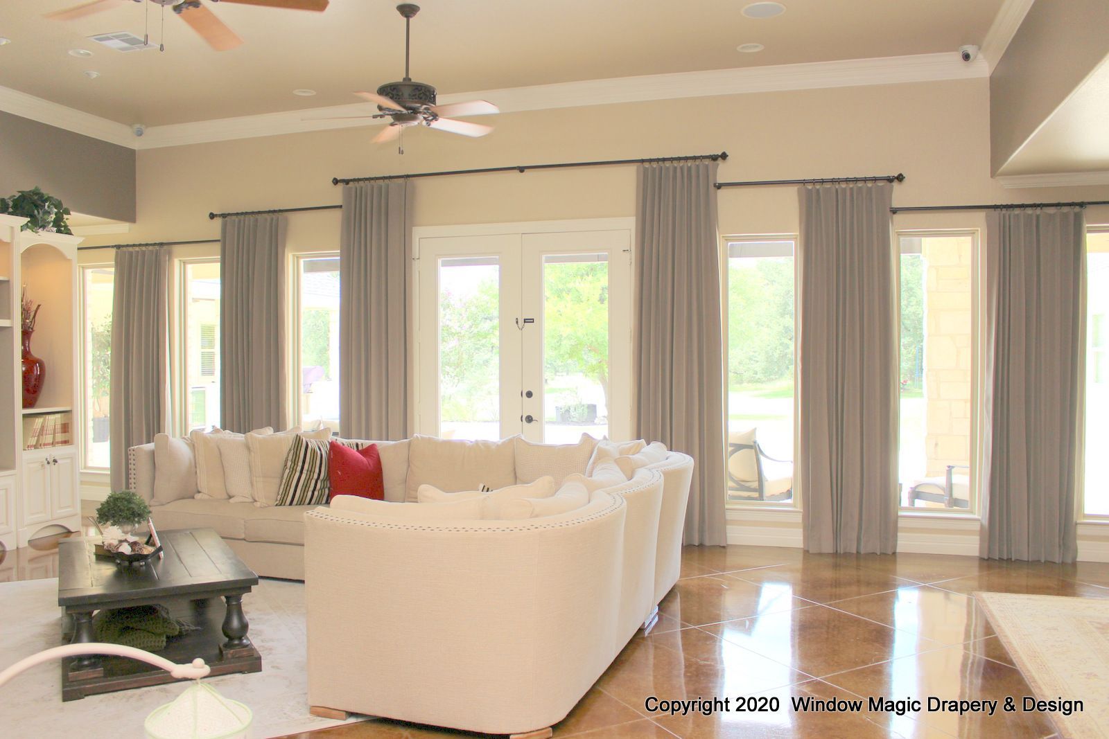 A living room with a large sectional couch and a ceiling fan
