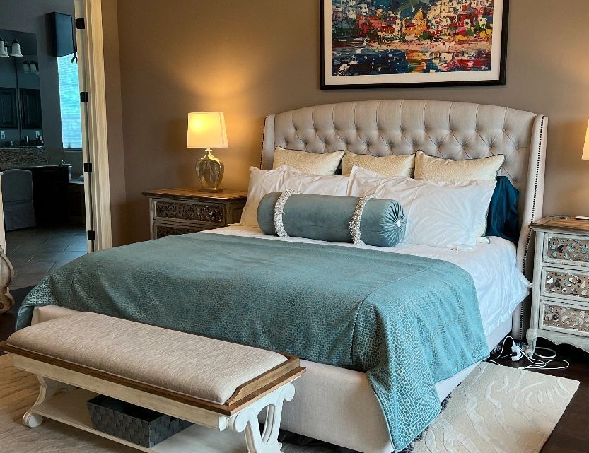A bedroom with a bed , nightstands , lamps and a bench