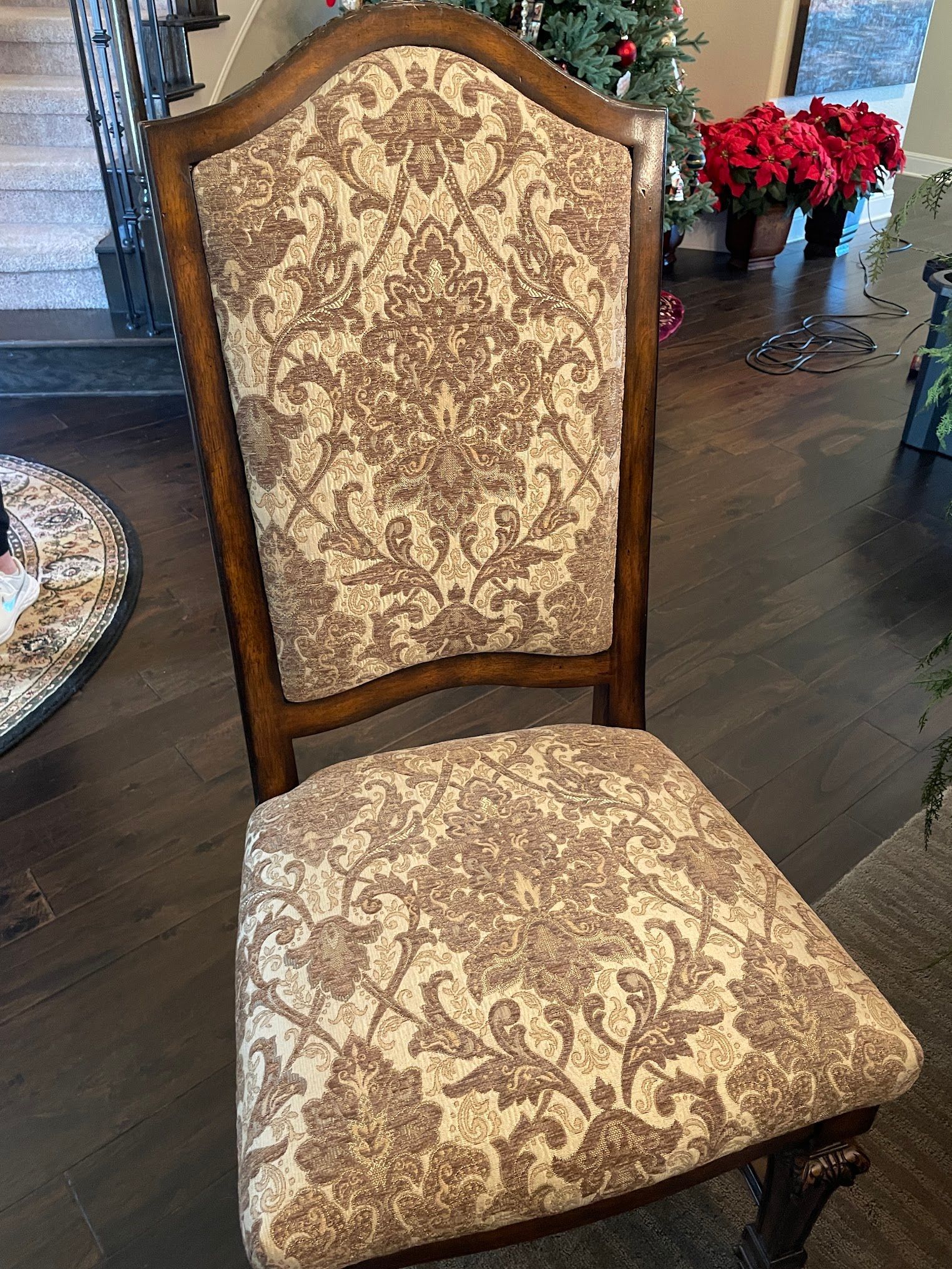 A chair with a pattern on it is sitting in a living room next to a christmas tree.