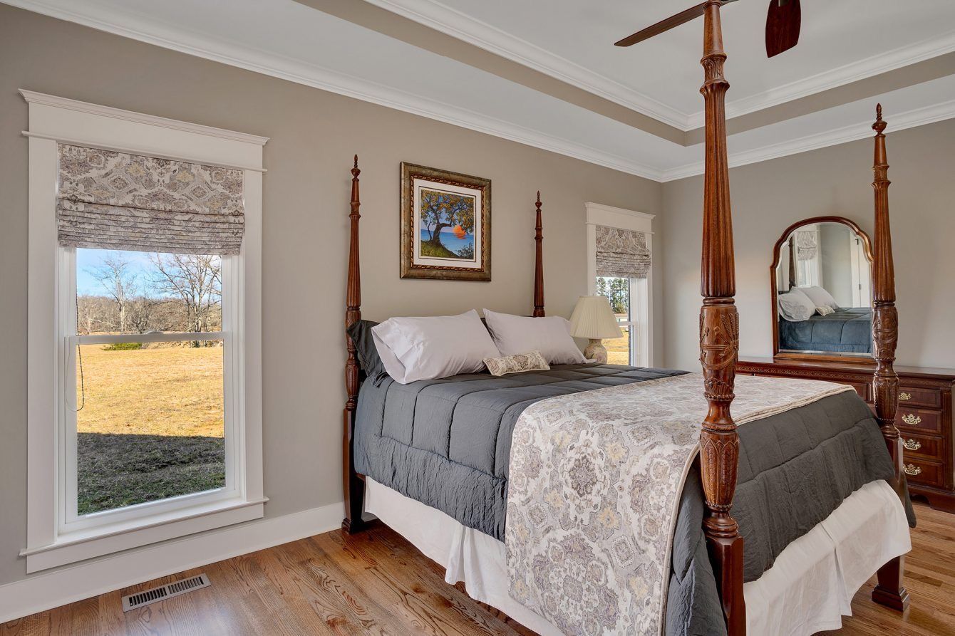 A bedroom with a four poster bed and a ceiling fan.