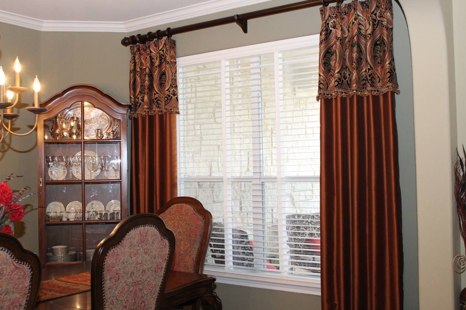 A dining room with a table and chairs and a window with blinds