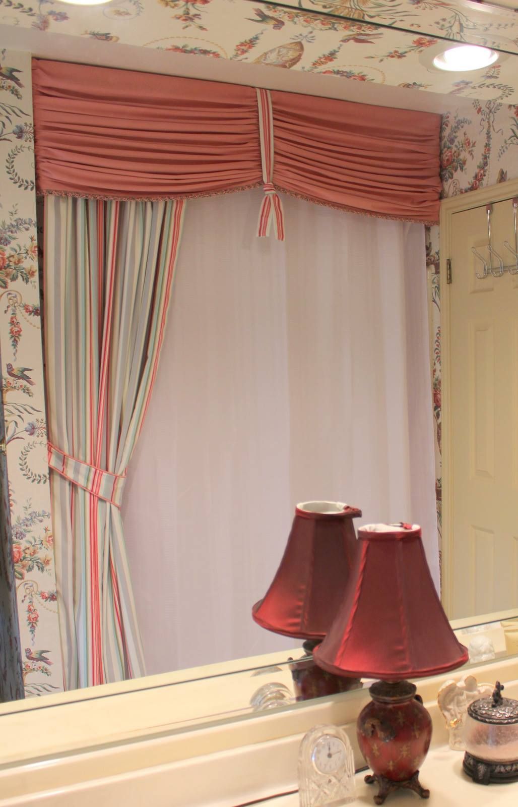 A bathroom with two lamps and a mirror.