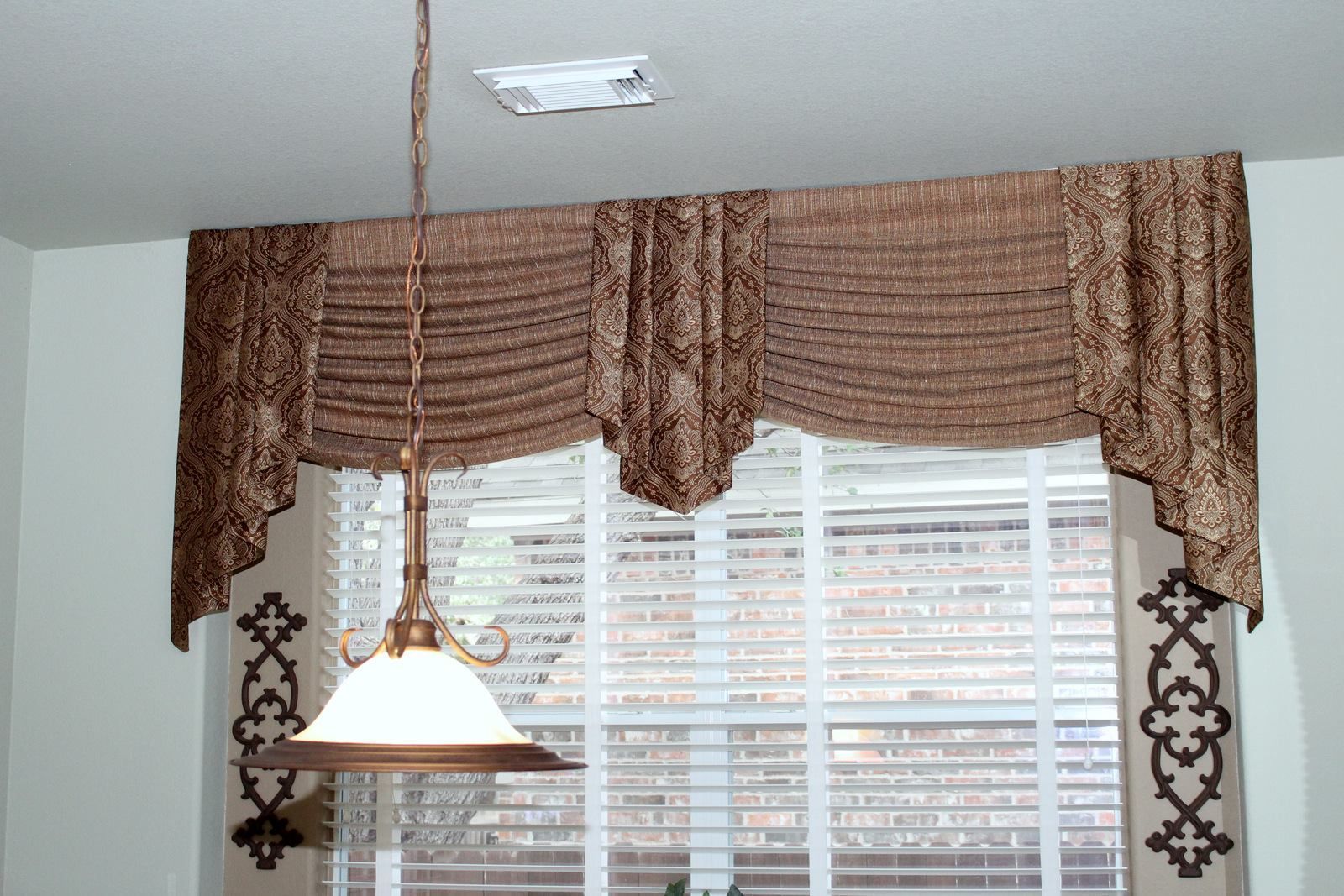 A window with blinds and a lamp hanging from the ceiling