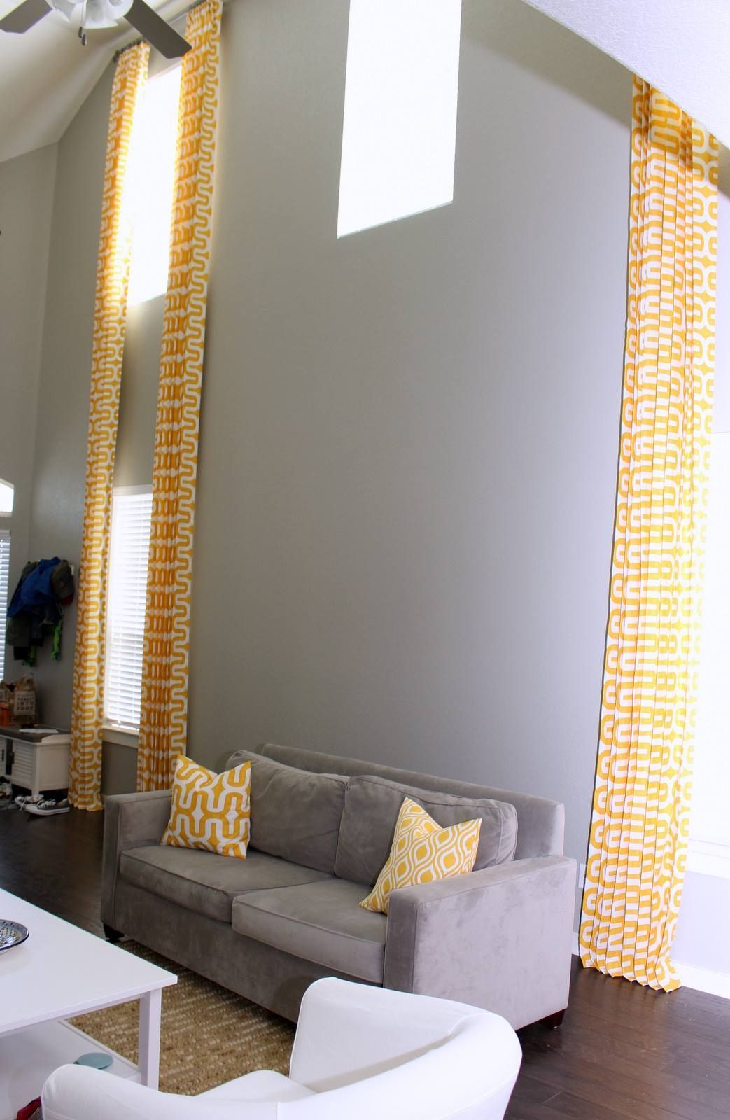 A living room with a gray couch and yellow curtains