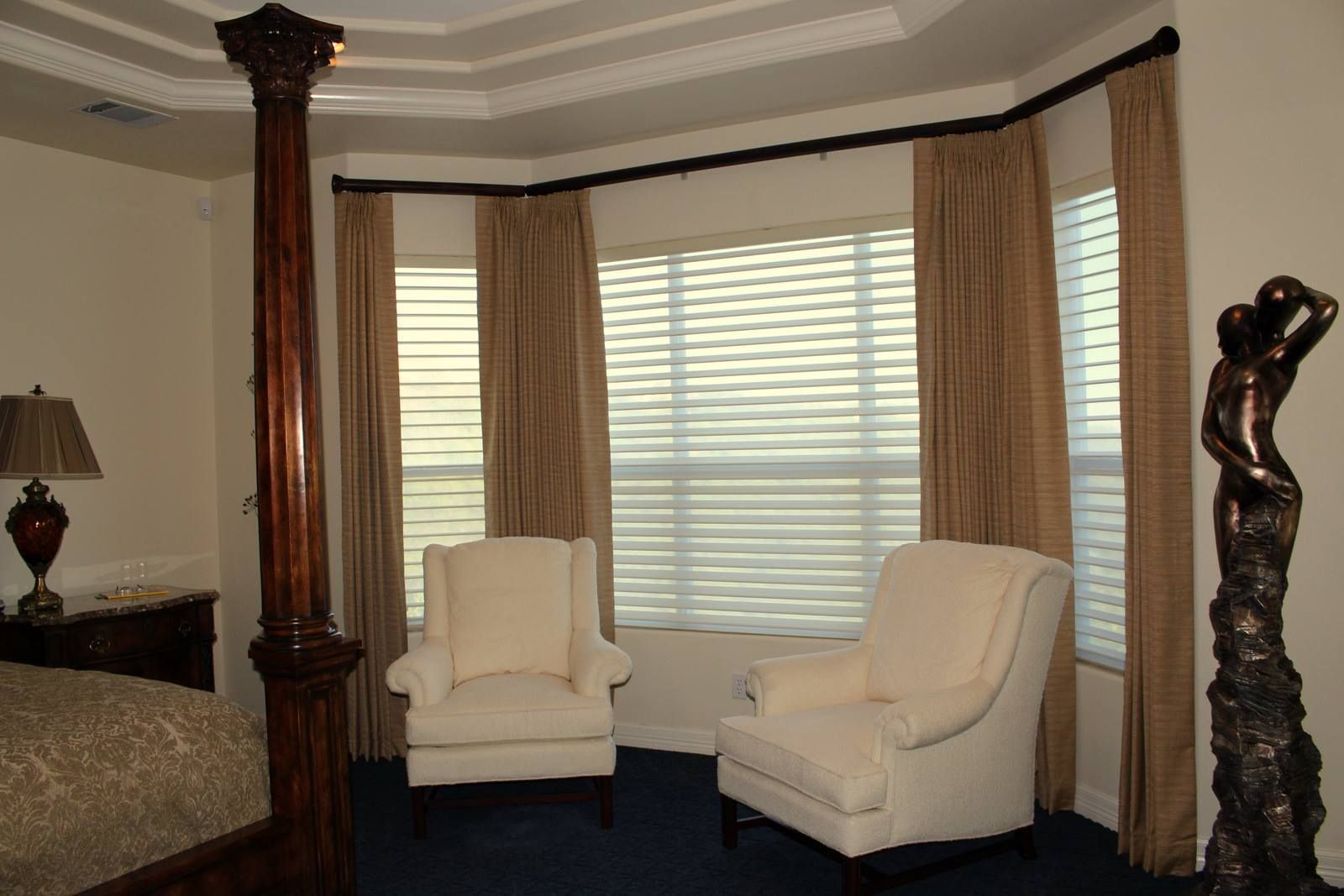 A bedroom with a four poster bed two chairs and a statue