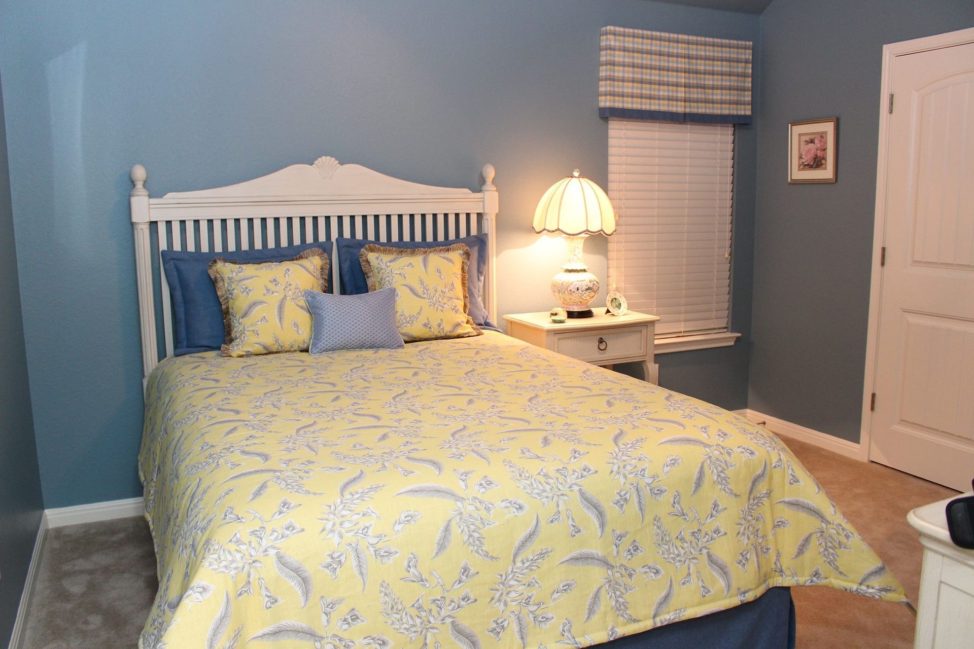 A bedroom with a bed , nightstand , lamp and window