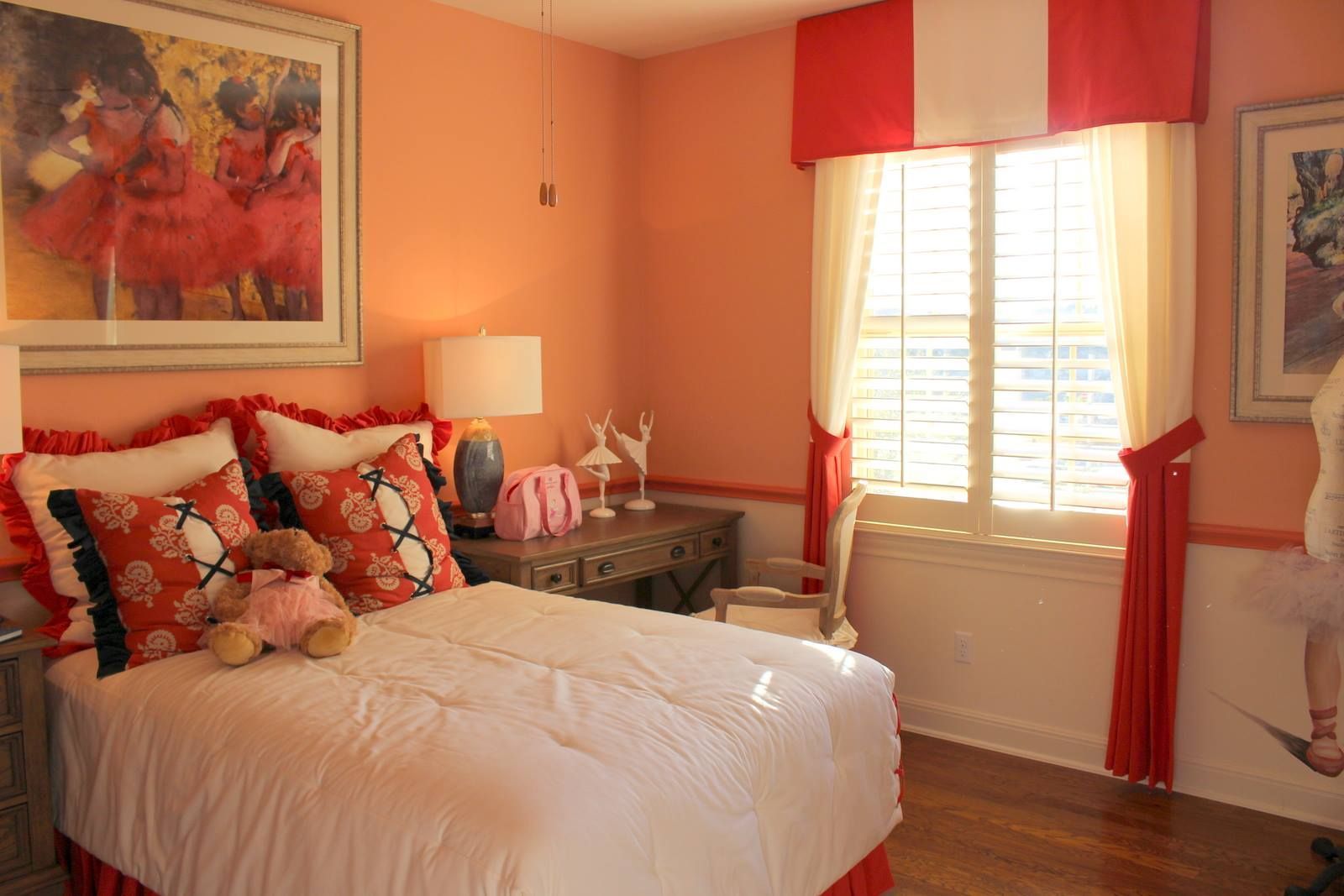 A girl 's bedroom with a bed , desk , lamps and a picture on the wall.