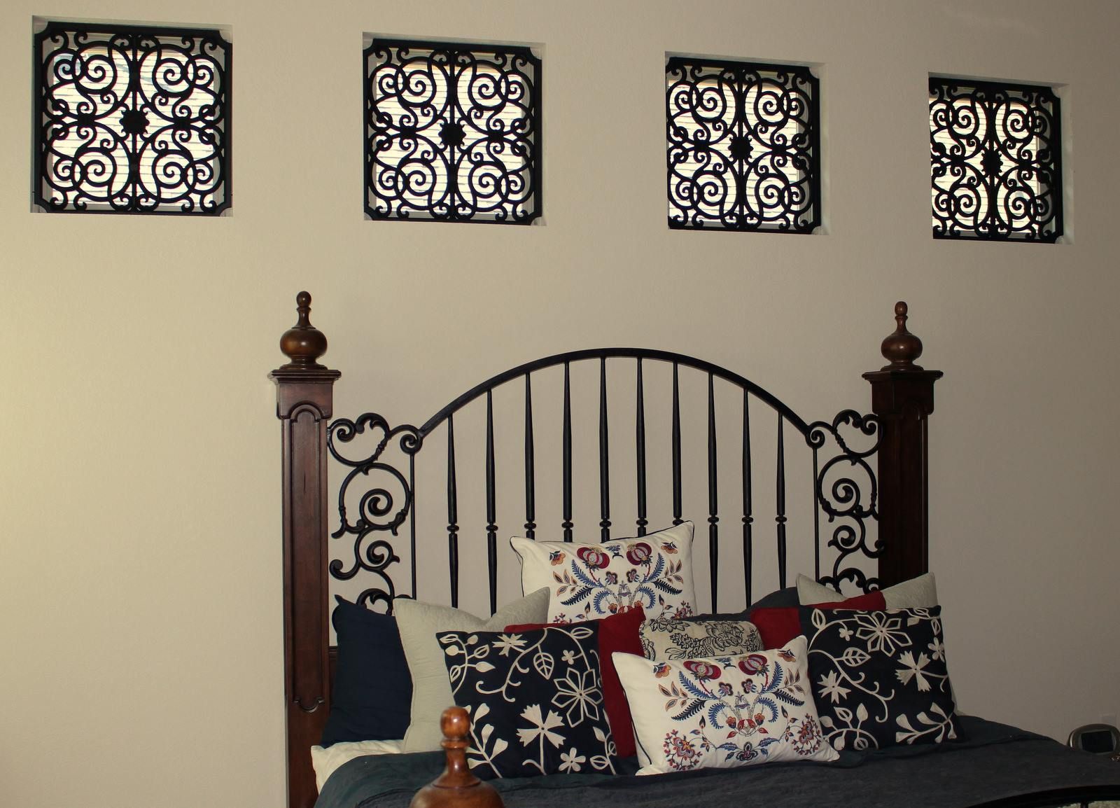 A bed with a wrought iron headboard and pillows