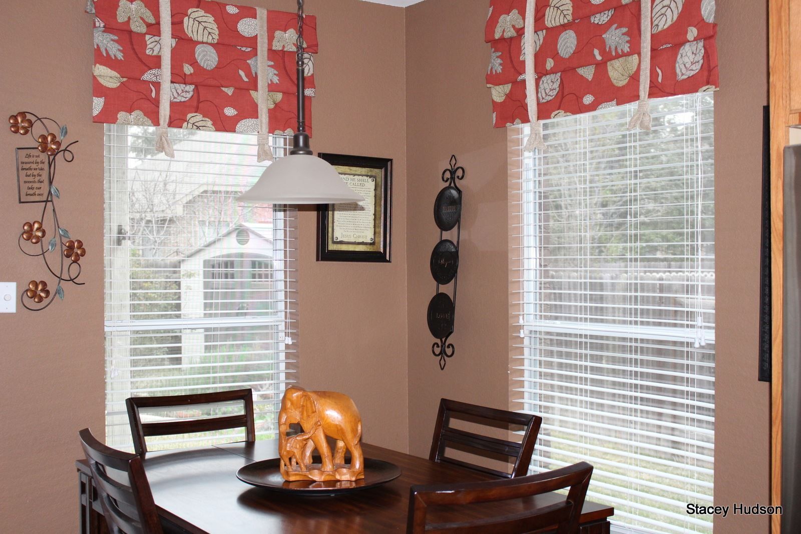 A dining room with a table and chairs in front of a window with blinds.