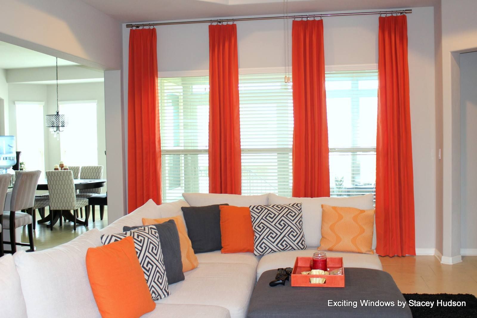 A living room with a sectional couch and orange curtains