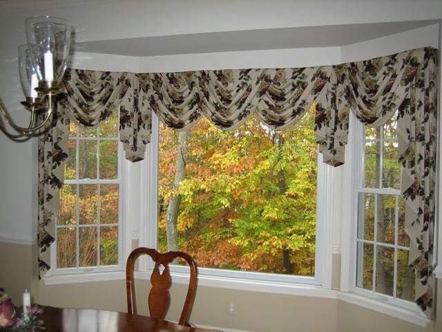 A dining room with a large bay window and a table and chairs