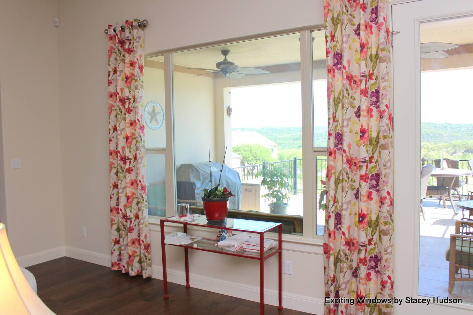 A living room with a large window and floral curtains