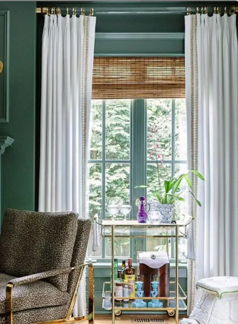 A living room with a chair and a bar cart in front of a window.