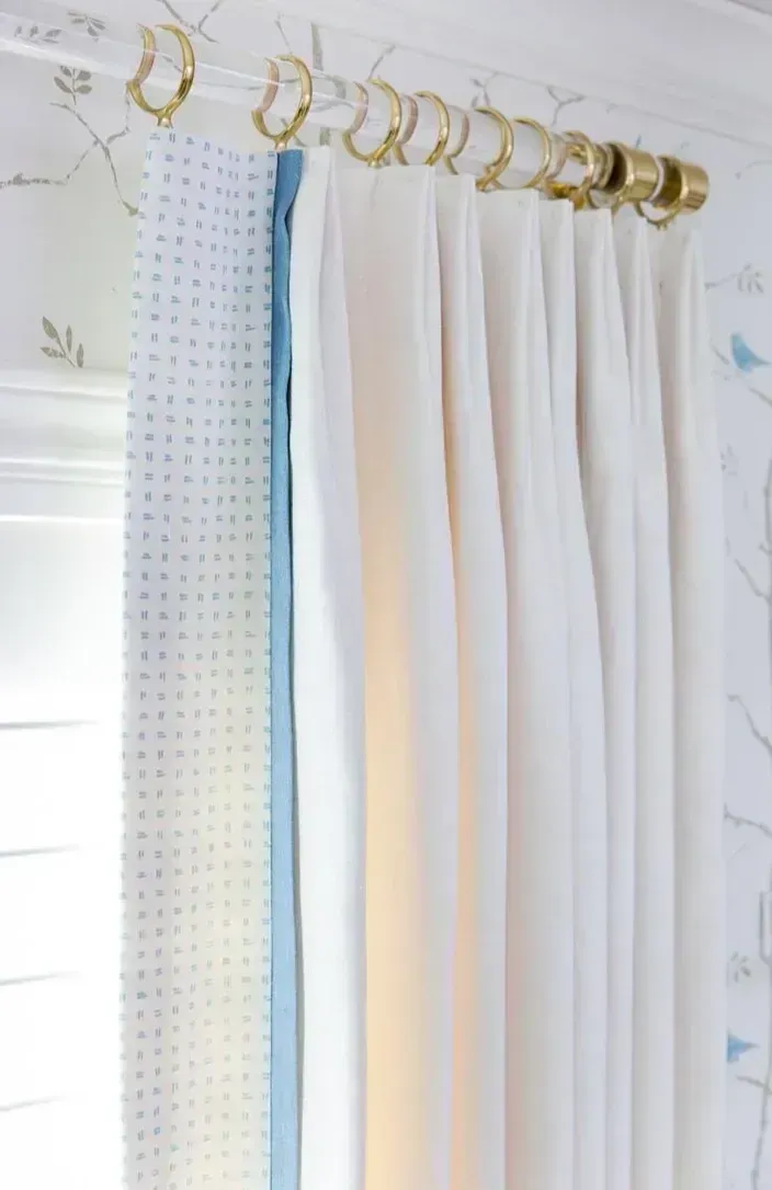 A pair of white curtains are hanging on a white curtain rod.