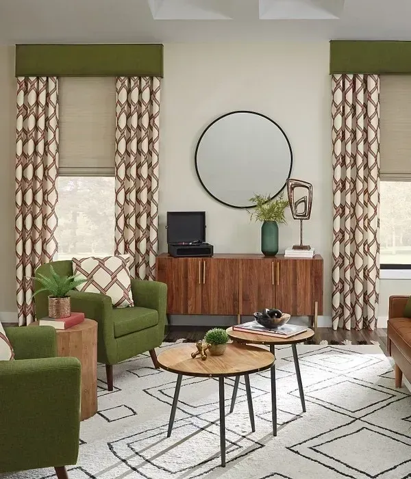 A living room with green chairs , tables and a mirror